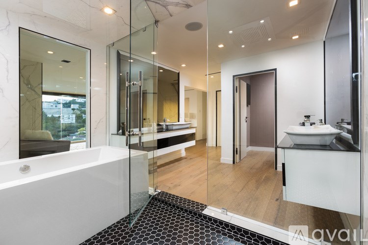 A bathroom with a white tub and a black and white tiled floor.