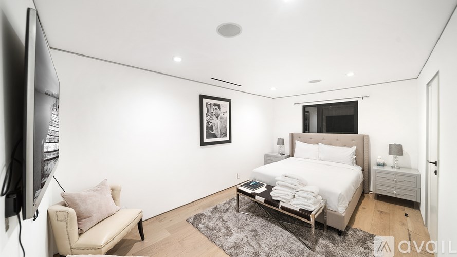 A room with a large painting of a building on the wall and a yellow mascot toy on the floor.