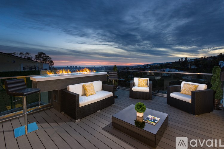 A patio with a table, chairs, and a view of the city at dusk.