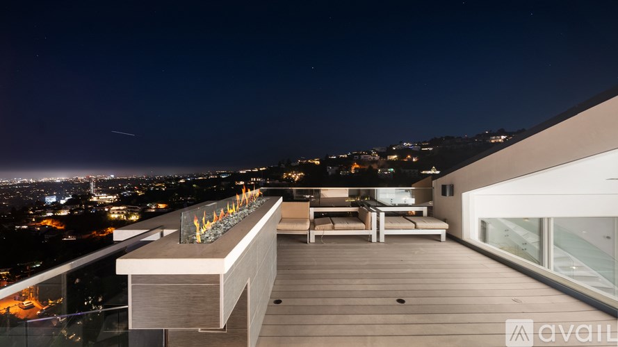 A living room with a glass table and black leather chairs.