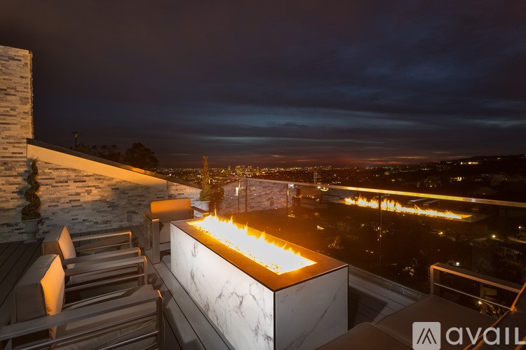 A modern outdoor seating area with a view of the city at night.