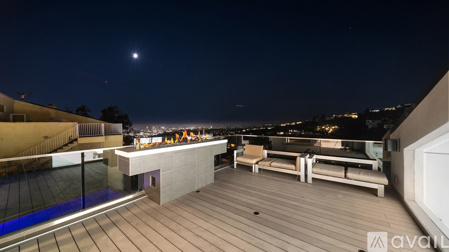 A rooftop deck with a bench and a view of the city at night.