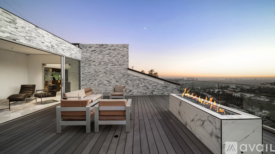 A modern outdoor patio with a fireplace and seating area.