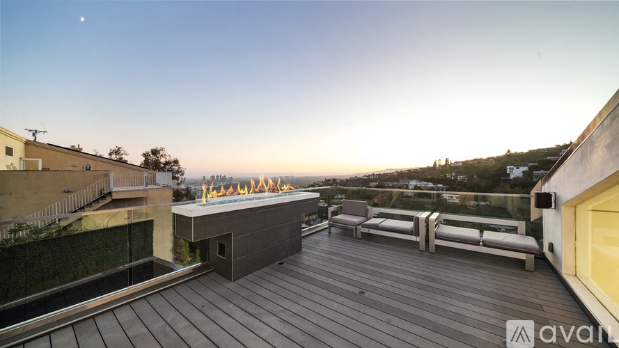 A rooftop deck with a bench and a view of the city at dusk.