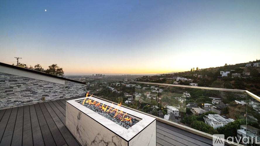 A modern outdoor kitchen with a view of the cityscape at dusk.