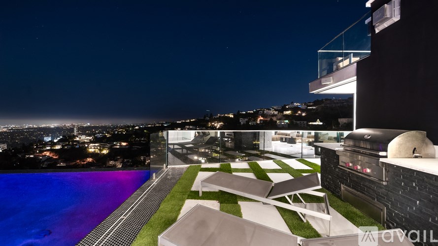 A modern house with a pool and a view of the city at night.