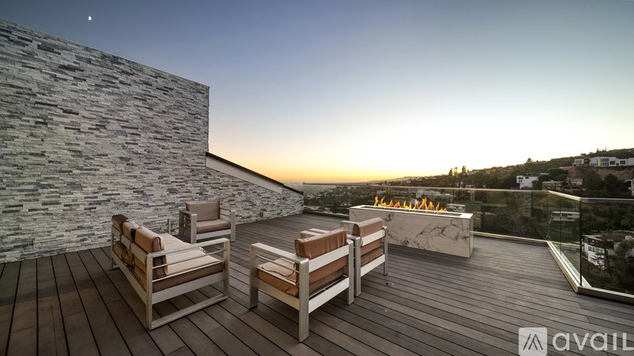 A wooden deck with two chairs and a table overlooking a sunset.