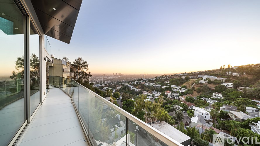 A modern balcony overlooks a cityscape at sunset.