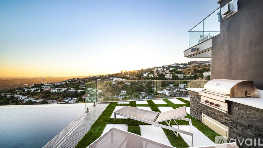 A modern house with a pool and a view of the city at sunset.