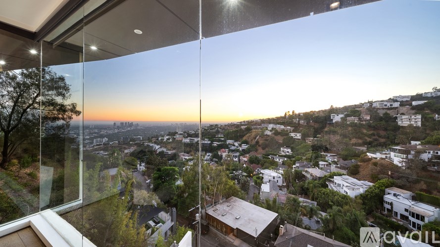 A view from a high-rise window looking out at a cityscape during sunset.