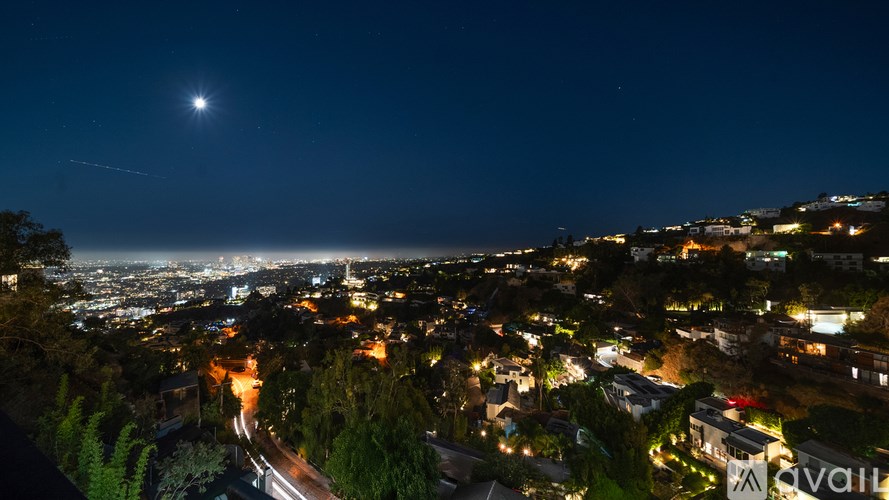 A nighttime cityscape with a bright moon and a shooting star.