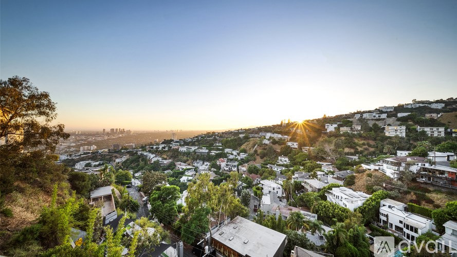 A sunset view of a residential area with houses and trees.