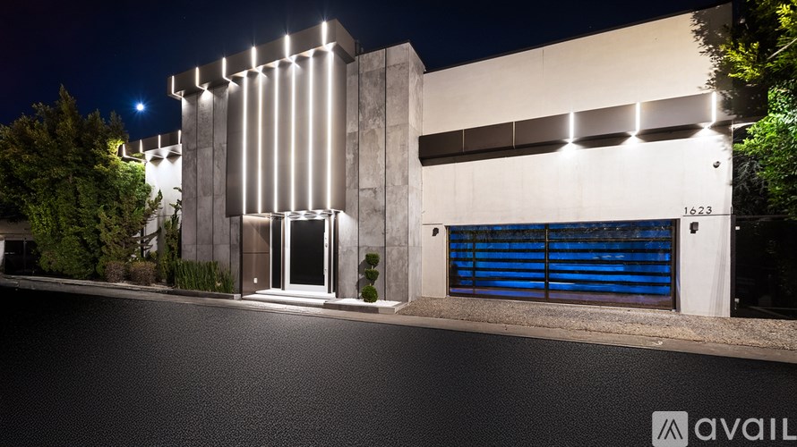 A modern building with a blue door and windows is illuminated at night.