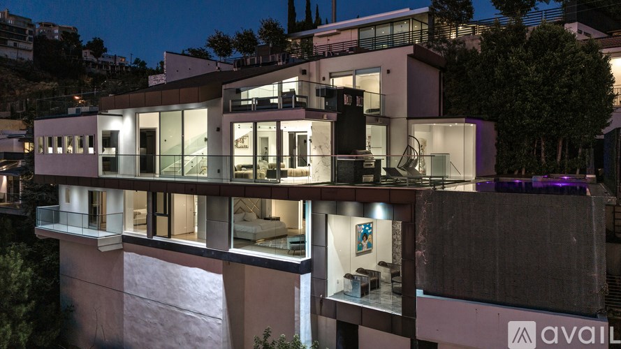 A modern house with a balcony and a lit up interior.