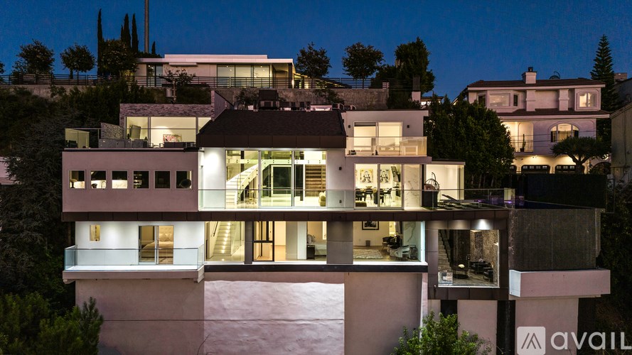 A modern house with a balcony and a lit up interior.