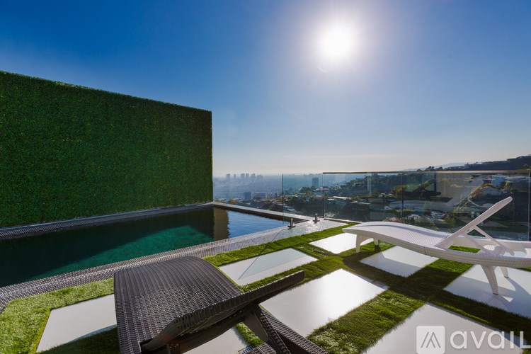 A modern building with a green wall and a pool in the foreground.