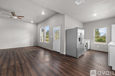 A spacious kitchen with wood flooring and a ceiling fan.