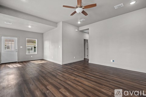 A spacious room with wooden flooring and a ceiling fan.