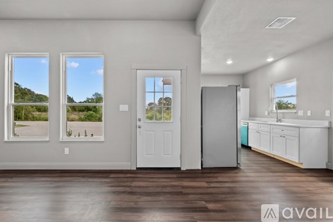 A spacious room with wooden floors and a large window overlooking a landscape.