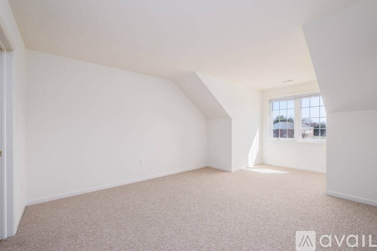 A large empty room with a carpeted floor and white walls.