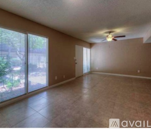 A room with a ceiling fan and sliding glass doors.