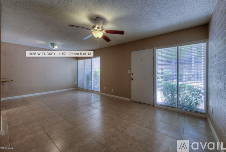 A spacious room with a ceiling fan and sliding glass doors leading to a patio.
