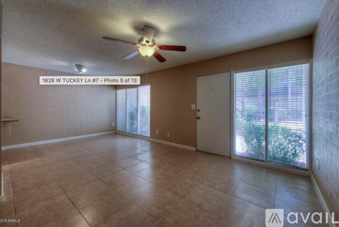 A spacious room with a ceiling fan and sliding glass doors leading to a patio.