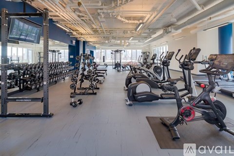 A gym with a variety of exercise equipment including treadmills, stationary bikes, and weight racks.