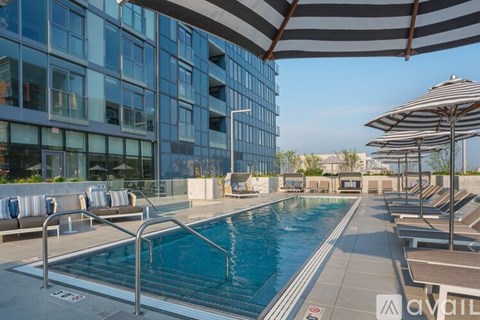 A large outdoor swimming pool with a striped umbrella.
