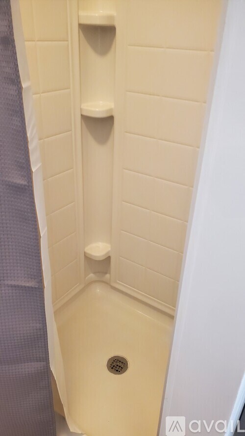 A white shower with a drain in the middle.