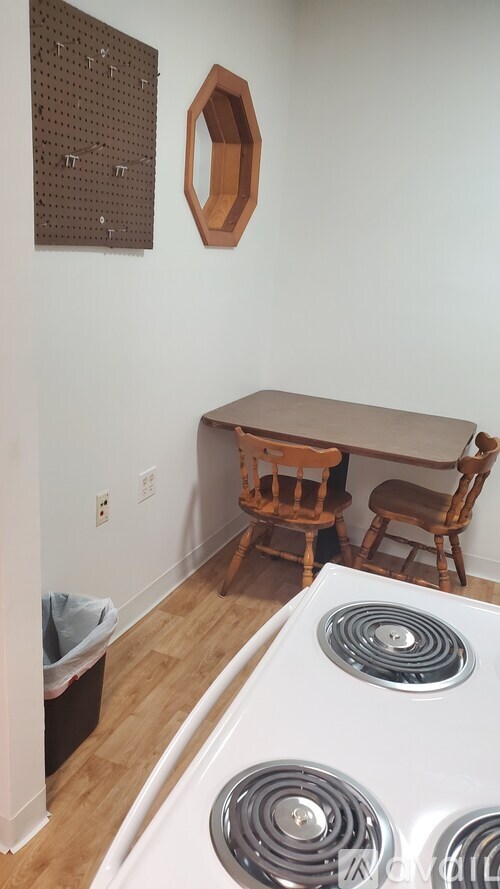 A white stove top oven sits in a kitchen with a wooden table and chairs.