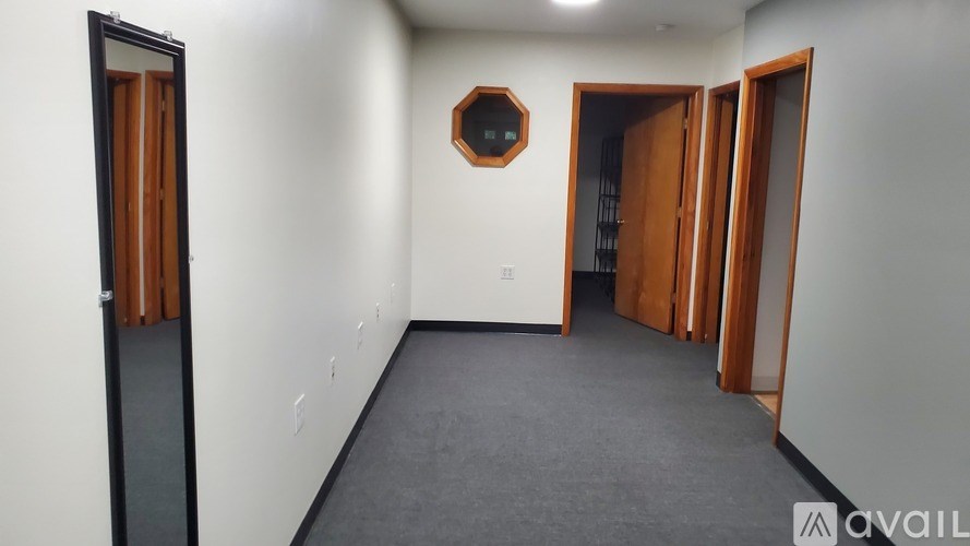 A room with a mirror on the wall and a door on the left.