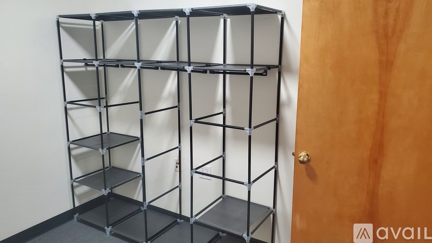 A tall, black metal shelving unit with multiple shelves is in a room.