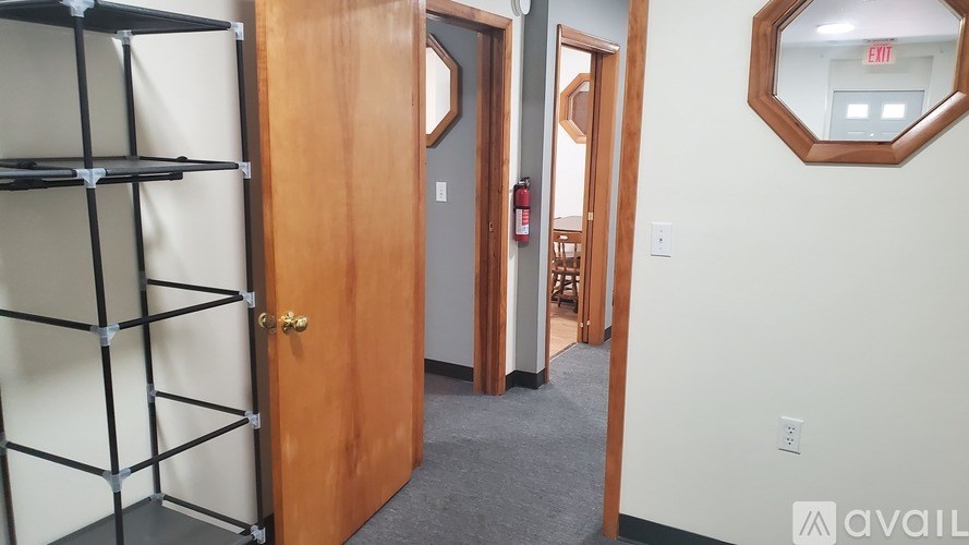 A hallway with a wooden door and a mirror on the wall.
