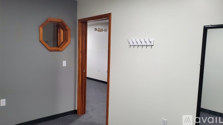 A room with a mirror, coat rack, and a door.