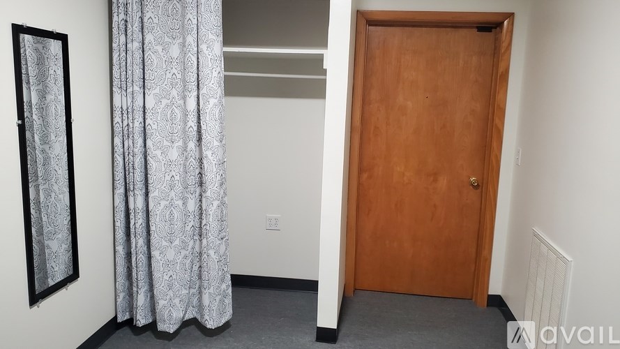 A room with a wooden door and a grey curtain.