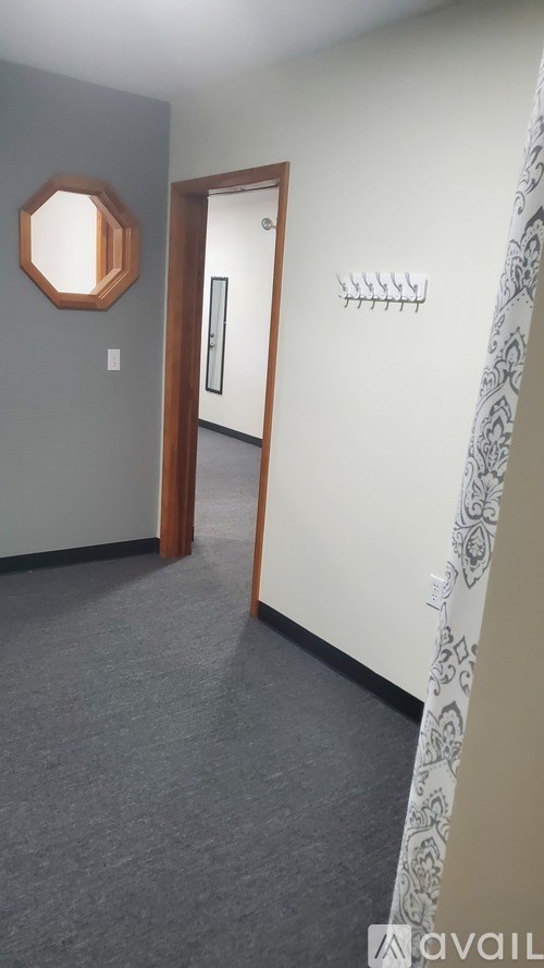 A hallway with a wooden door and a wall-mounted light fixture.