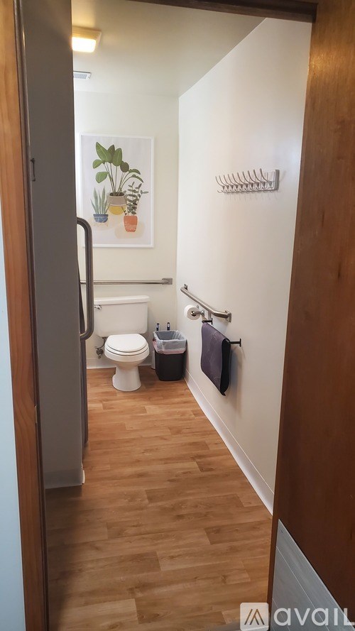 A bathroom with a toilet, sink, and a plant on the wall.