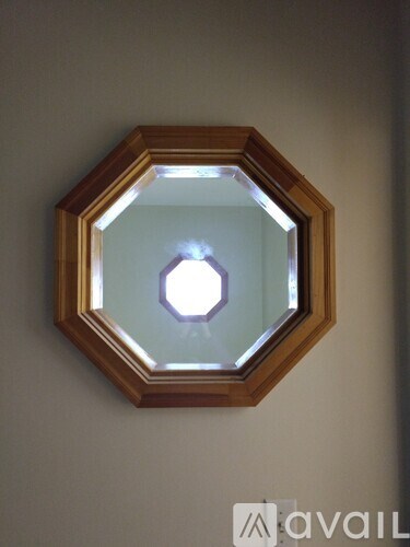A hexagonal mirror with a wooden frame is hanging on the wall.