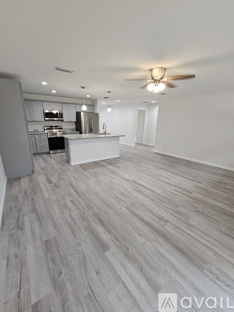 A spacious kitchen with a refrigerator on the left and a dining area in the background.