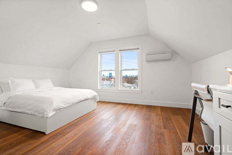 A bedroom with a large bed and a window overlooking a cityscape.