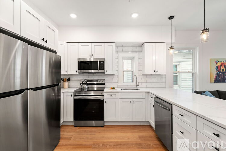 A modern kitchen with a stainless steel refrigerator and white cabinets.