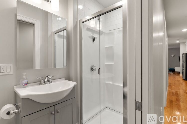 A bathroom with a sink, mirror, and shower.