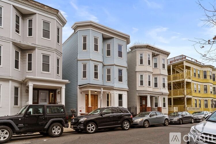 A row of townhouses with cars parked in front.