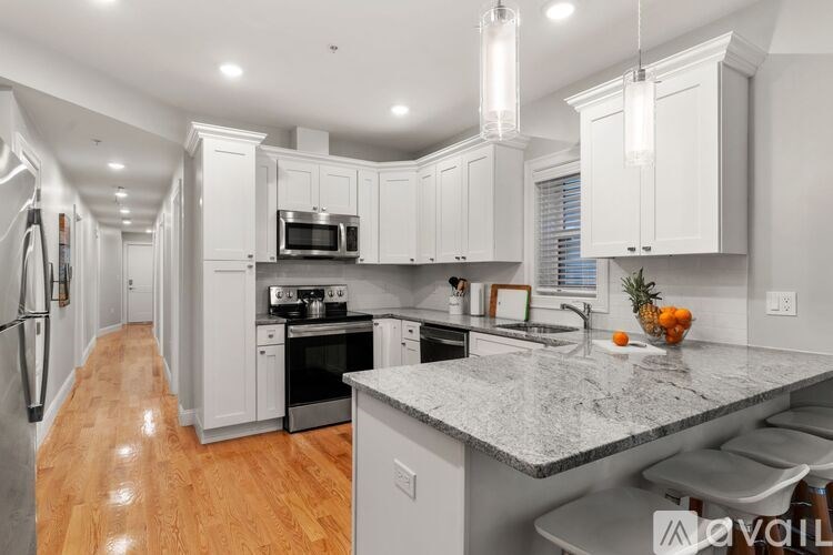 A kitchen with white cabinets and a marble countertop.