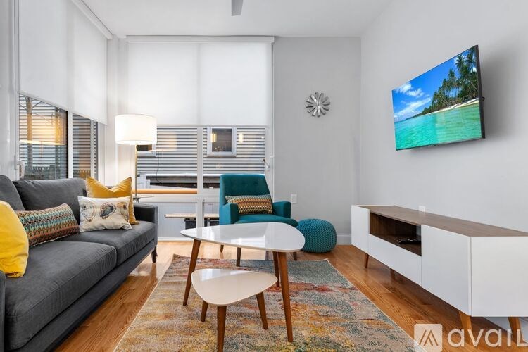 A living room with a grey couch, a white coffee table, and a flat screen TV mounted on the wall.