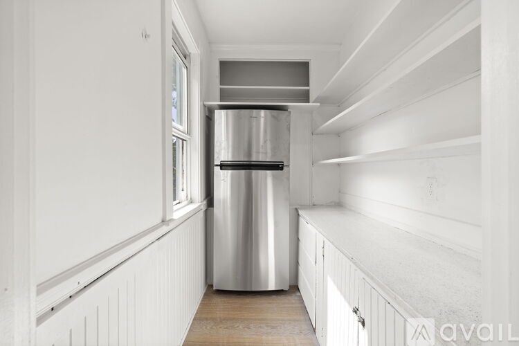 A kitchen with white cabinets and a stainless steel refrigerator.