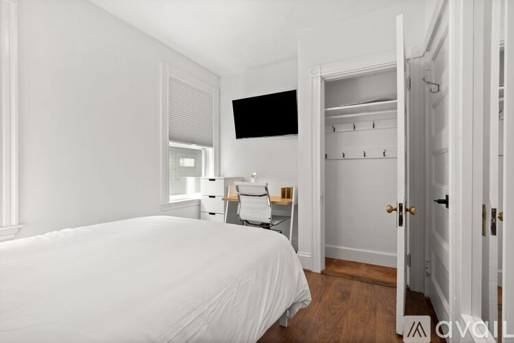 A bedroom with a bed, a desk, and a wardrobe.