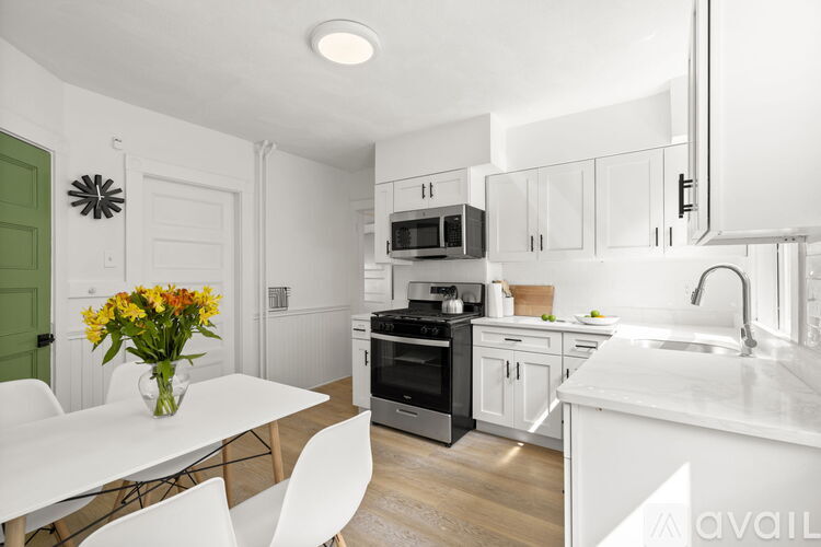 A kitchen with white cabinets and a green door.