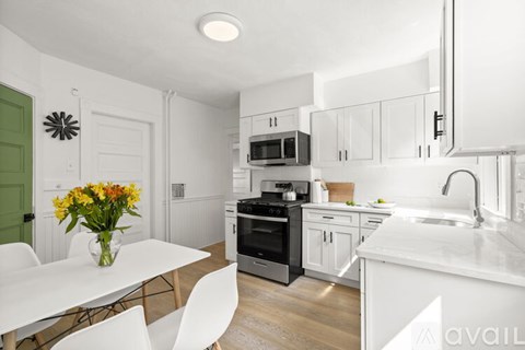 A kitchen with white cabinets and a green door.